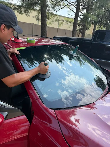MCA technician polishing a freshly installed windshield on a red car