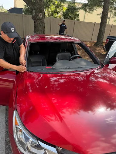 MCA installer setting a new windshield into a red sedan